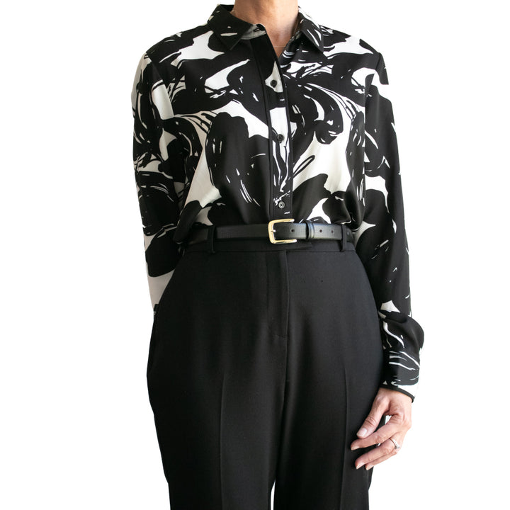 Black and white patterned shirt with a belt and black pants on a white background