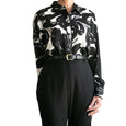 Black and white patterned shirt with a belt and black pants on a white background