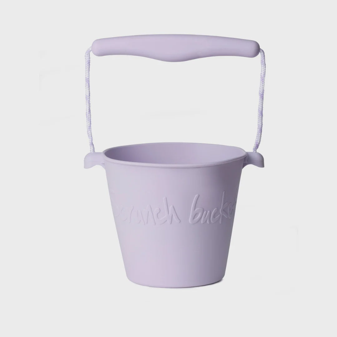 A light purple plastic bucket with a matching curved handle and rope loop, featuring embossed text that reads 'someday bucket' on the front, set against a plain light gray background.