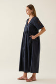 Woman wearing a navy blue isle of mine dress on a plain background