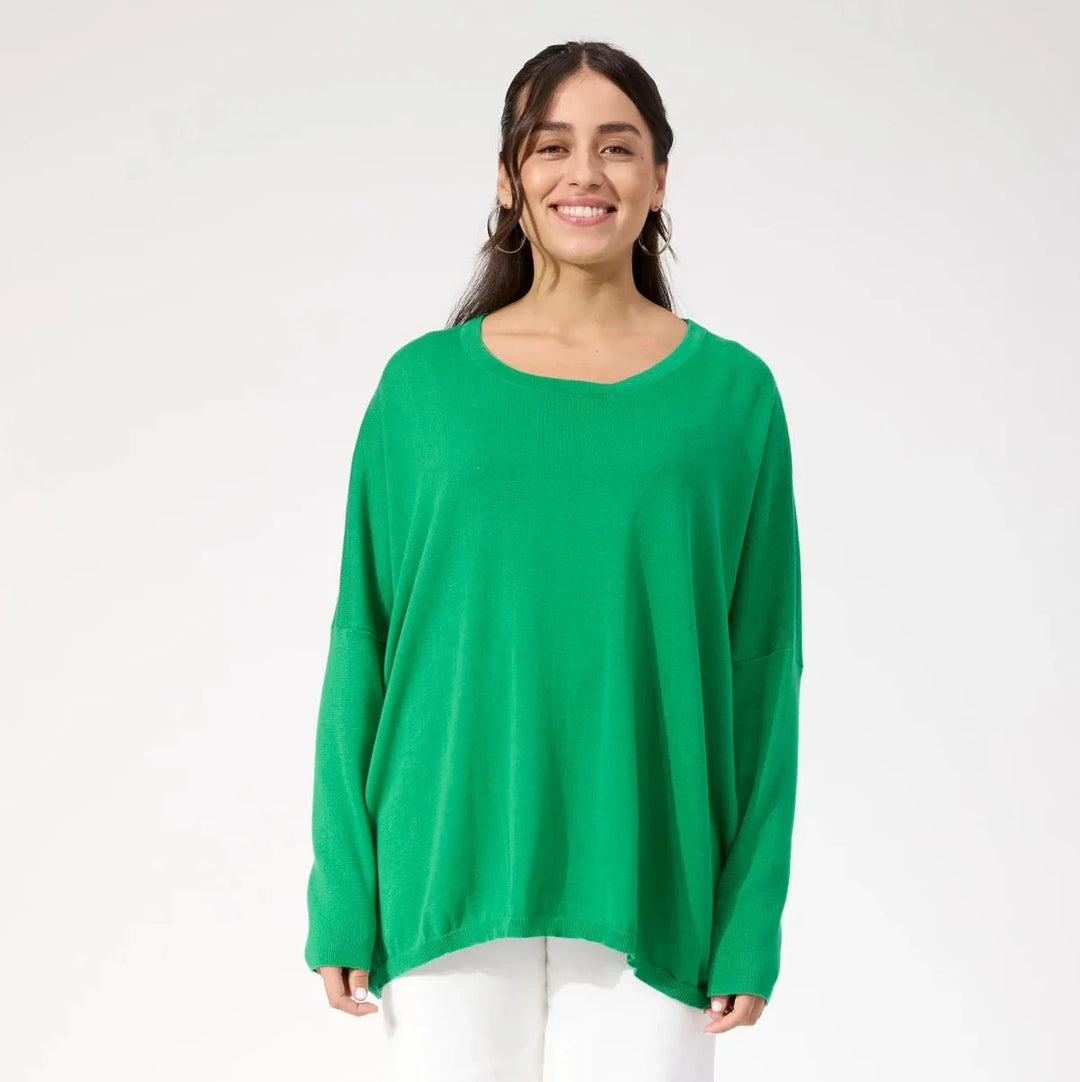Woman wearing a green sweater and white pants on a white background
