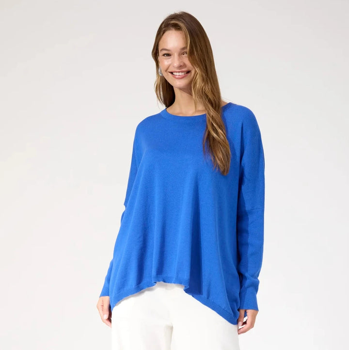 Woman wearing a blue top and white pants on a white background