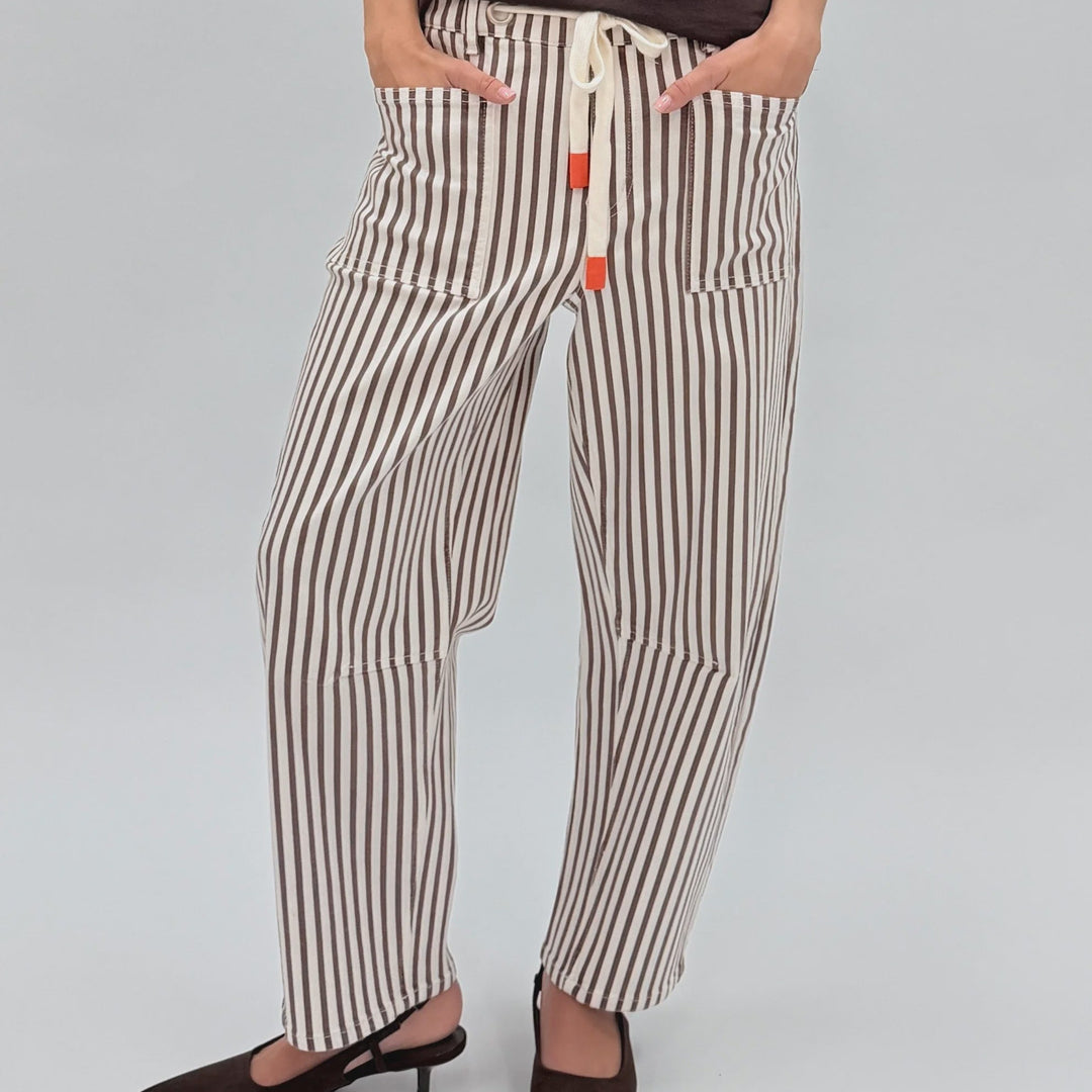 Woman wearing a brown t-shirt and striped pants against a white background