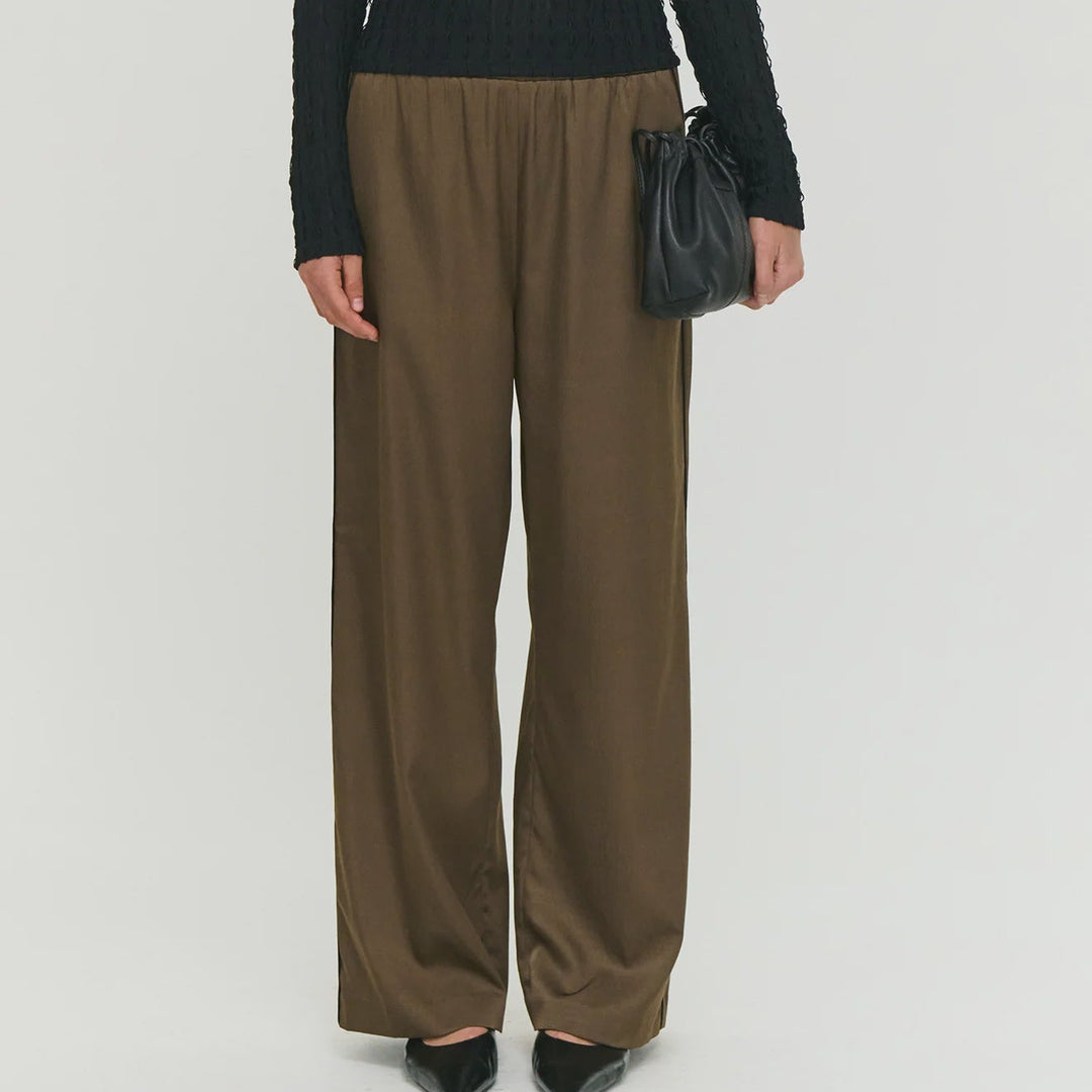 Woman wearing a black sweater and brown pants with sunglasses on a white background