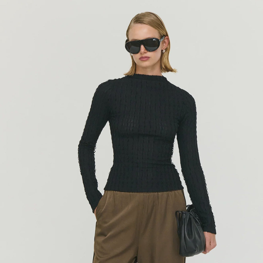 Woman wearing a black top and brown pants on a white background