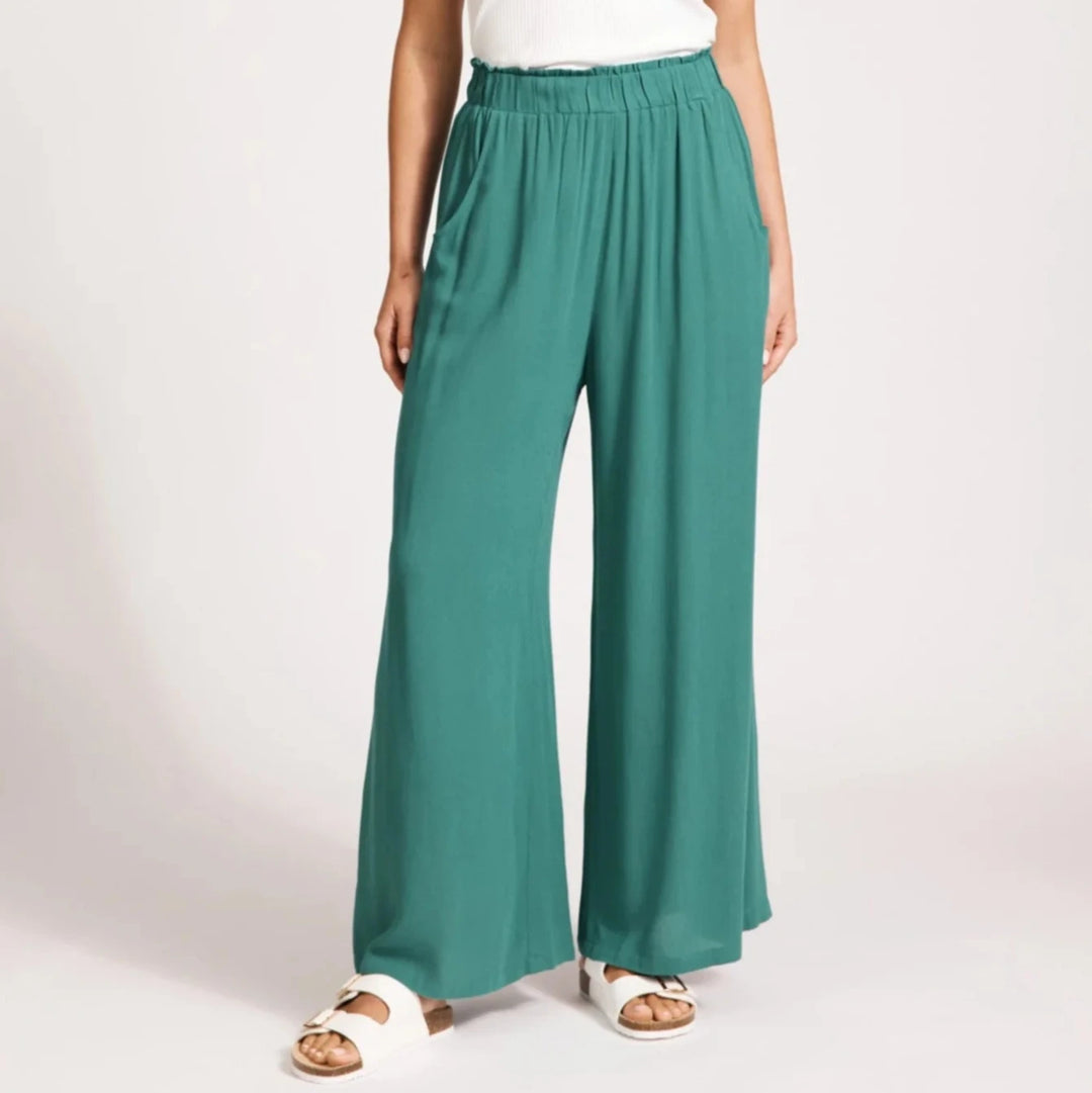Woman wearing Eb & Ive teal wide-leg pants and a white top on a light background