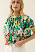 Woman wearing a colorful isle of mine patterned blouse against a plain background