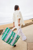 Woman holding a green and white striped cooler bag by the beach
