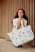 Woman holding a large cooler tote bag with blue patterns against a wooden background