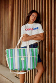 Woman holding a striped cooler tote bag against a wooden wall