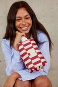 Woman holding a red and white checkered bag against a neutral background