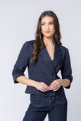 Woman wearing a navy billie the label blazer and jeans against a light gray background
