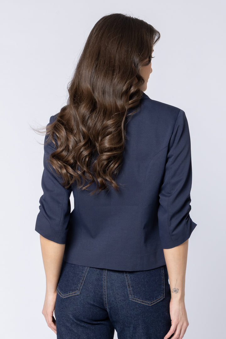 Woman wearing a navy seeking lola blazer and jeans on a white background