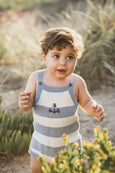 Child wearing a striped Bebe bodysuit with an anchor design outdoors.