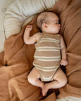 Baby in a striped Bear romper lying on a brown blanket