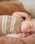 Newborn baby sleeping peacefully on a brown blanket