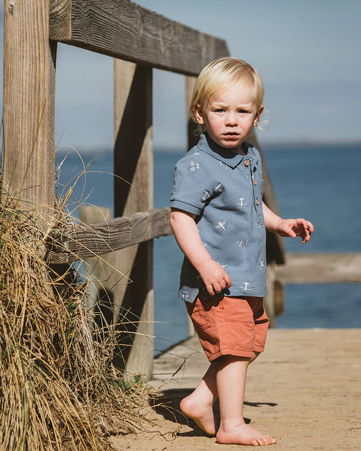 Young boy standing on a wooden dock by the ocean