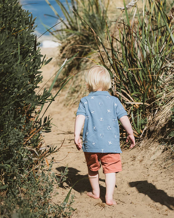 Child walking on a dirt path surrounded by plants