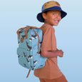 Child wearing a blue backpack with whale pattern against a light blue background