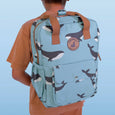 Person wearing a blue backpack with whale pattern on a light blue background