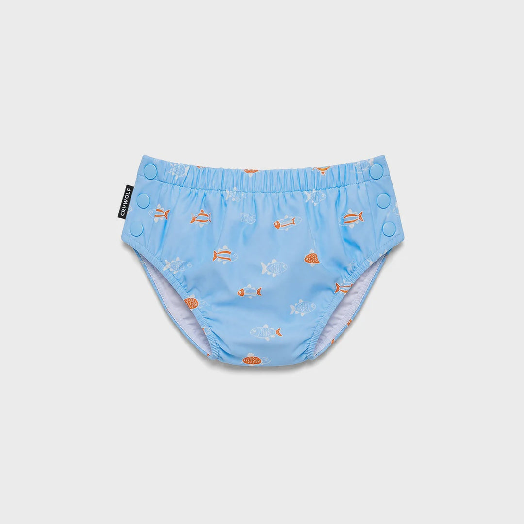 Light blue reusable swim diaper with an orange and white fish pattern, featuring a waistband with snap closures and a black brand tag reading 'KAVU'.