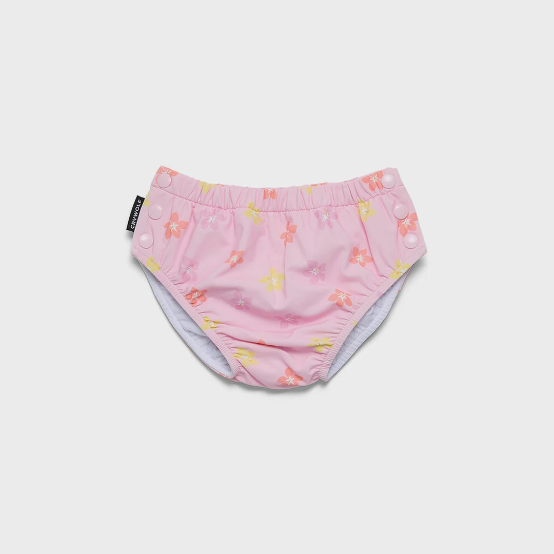 A pair of pink reusable swim diapers with a colorful floral pattern, featuring an elastic waistband and snap closures, shown on a plain white background.
