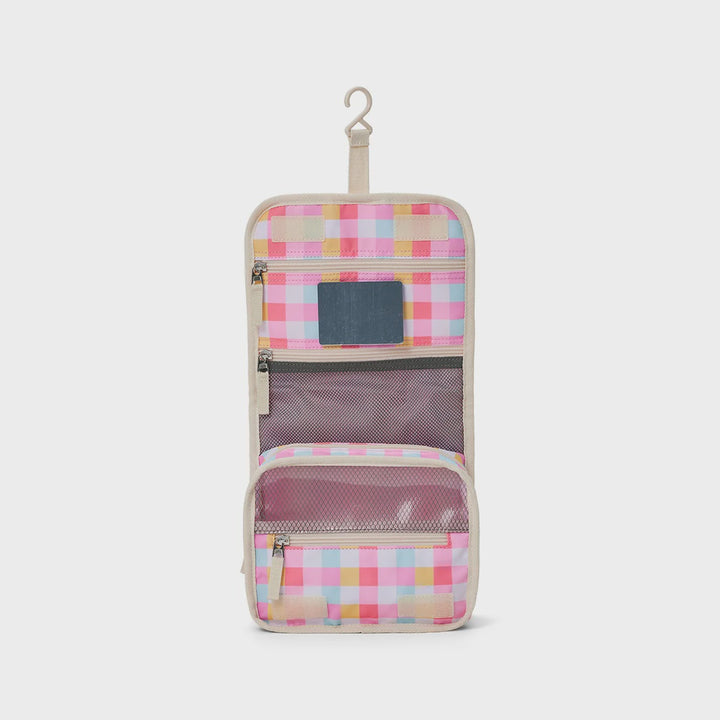 A hanging toiletry bag with a pastel pink, yellow, and blue checkered pattern, featuring multiple zippered compartments and mesh pockets, shown on a plain white background.