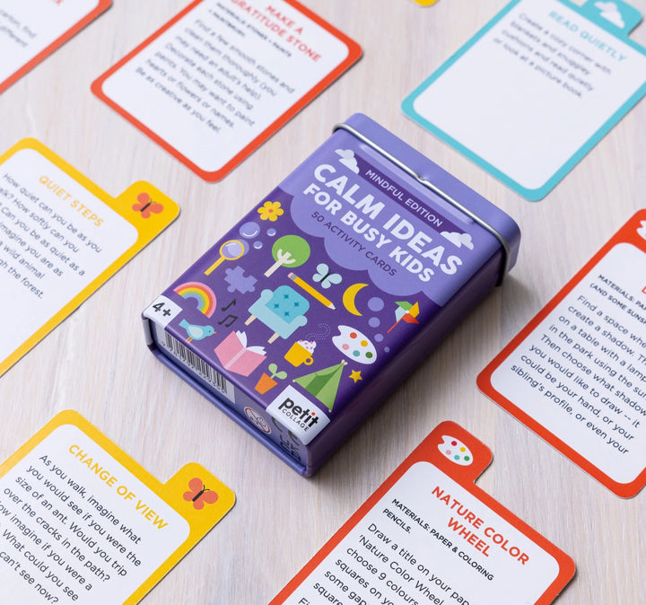 Purple card game box labeled 'Calm Ideas for Busy Kids' surrounded by colorful activity cards on a light wooden surface.