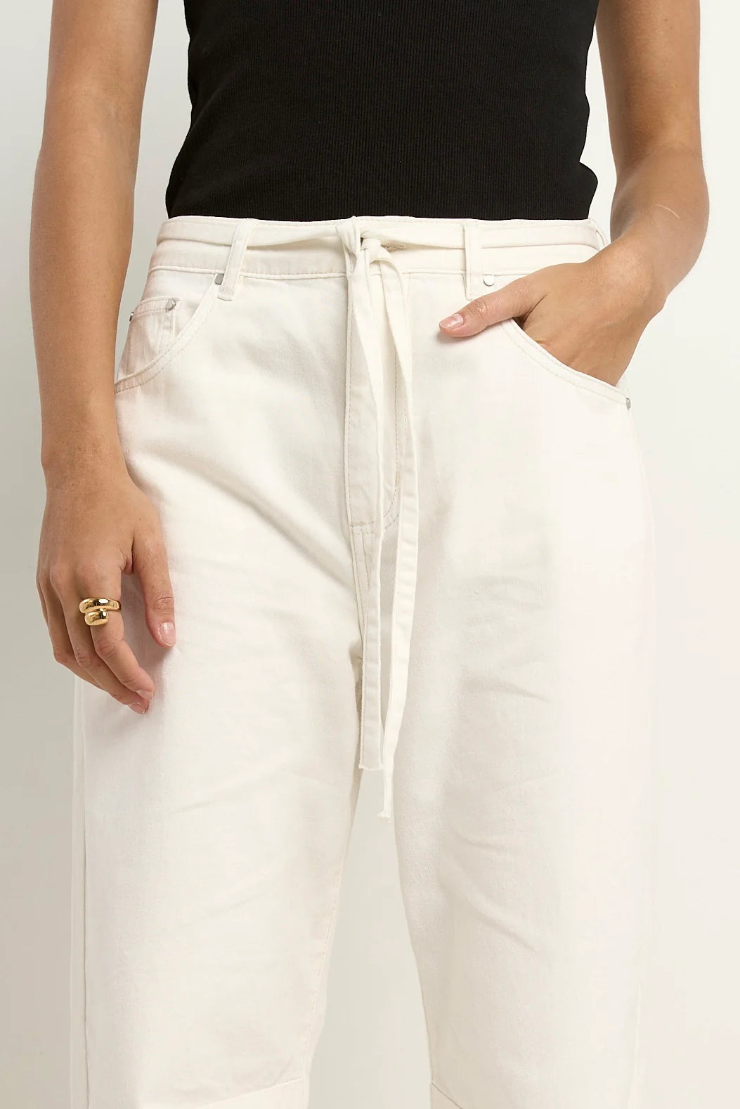 Person wearing white pants and a black top on a plain background