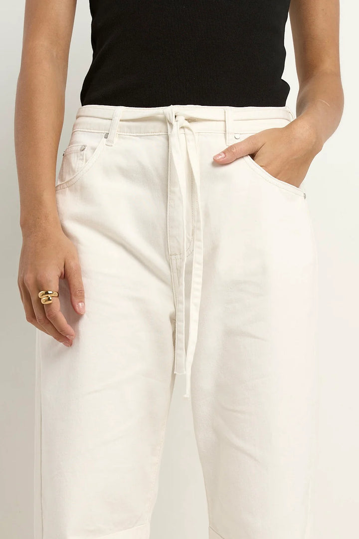 Person wearing white pants and a black top on a plain background