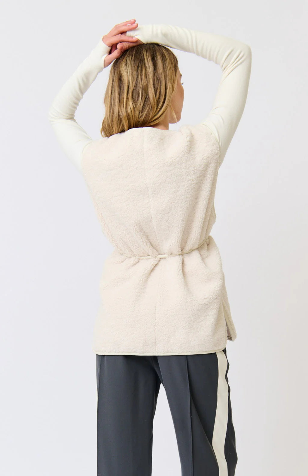 Person wearing a cream-colored sweater with a plain background
