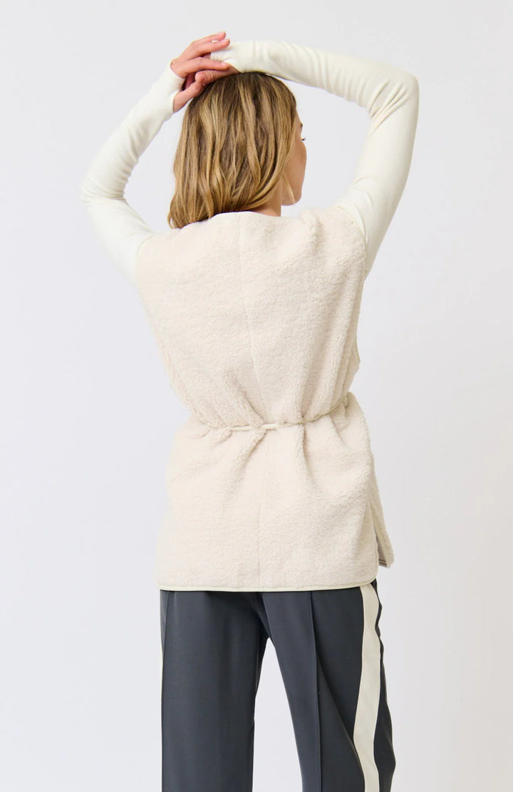 Person wearing a cream-colored sweater with a plain background