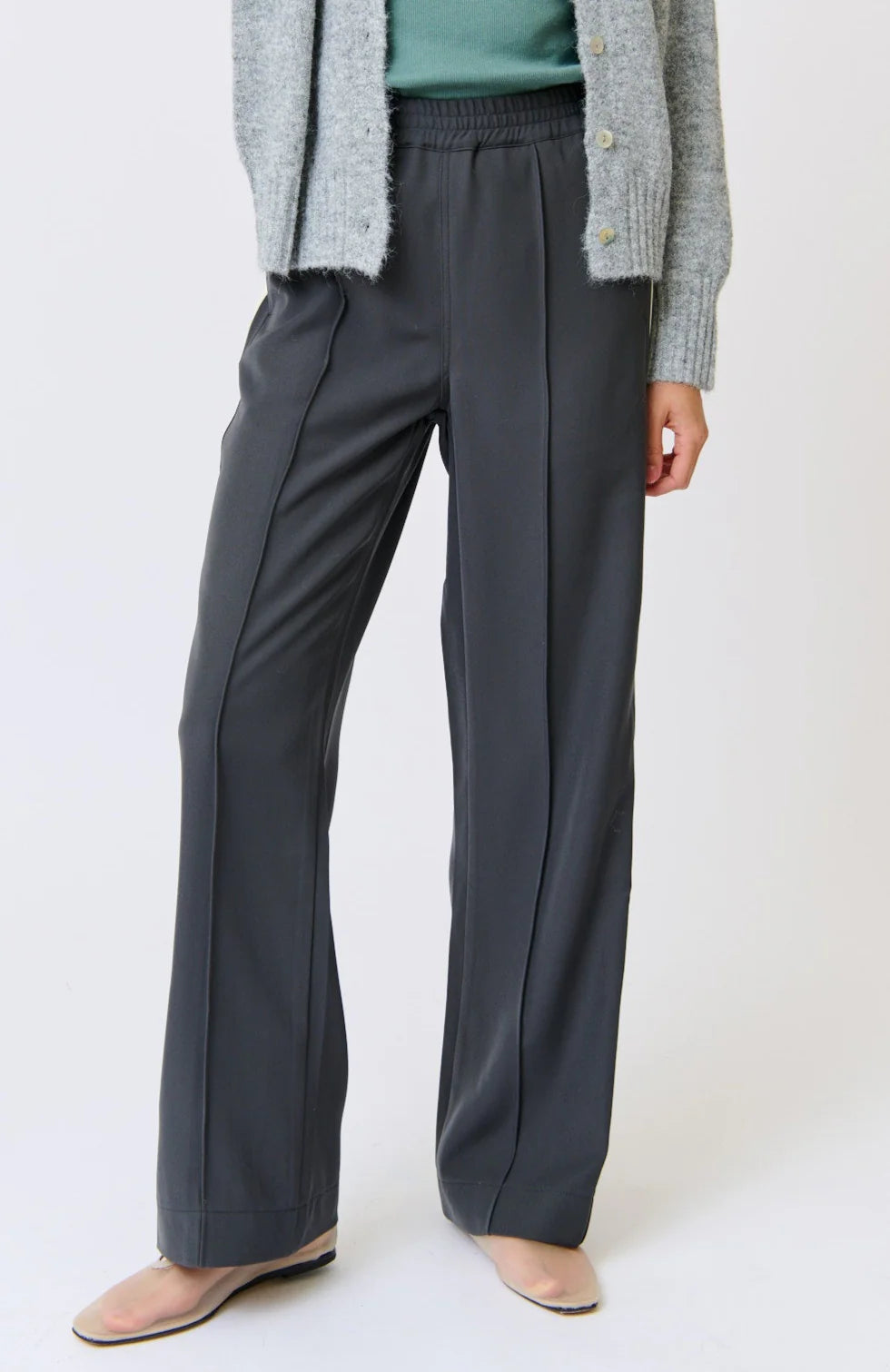 Person wearing gray wide-leg pants and a light gray cardigan on a white background