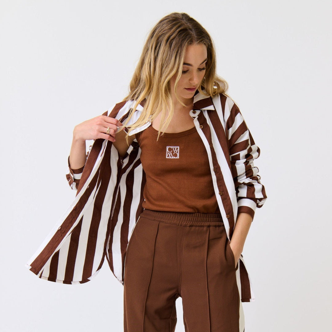 Woman wearing a brown outfit with a striped jacket on a white background