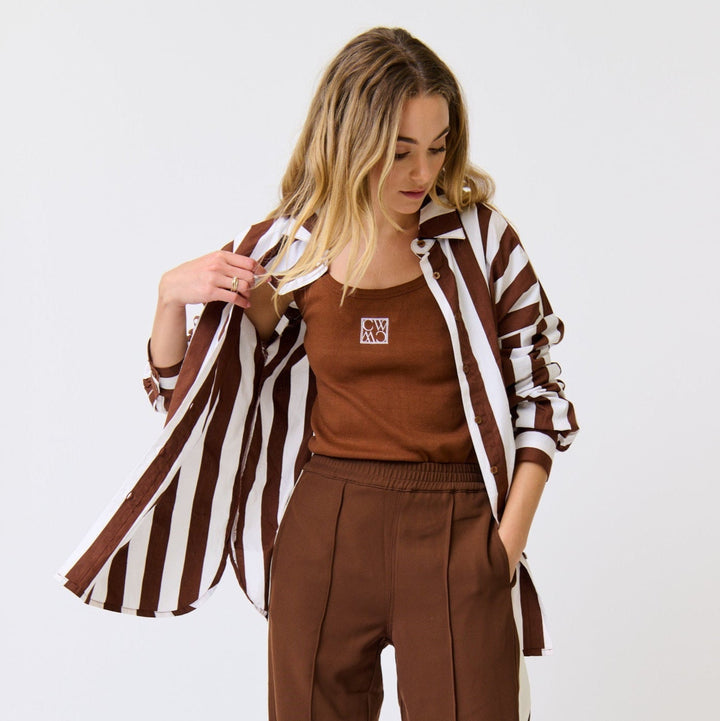 Woman wearing a brown outfit with a striped jacket on a white background