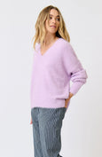 Woman wearing a light purple sweater and gray pants on a white background