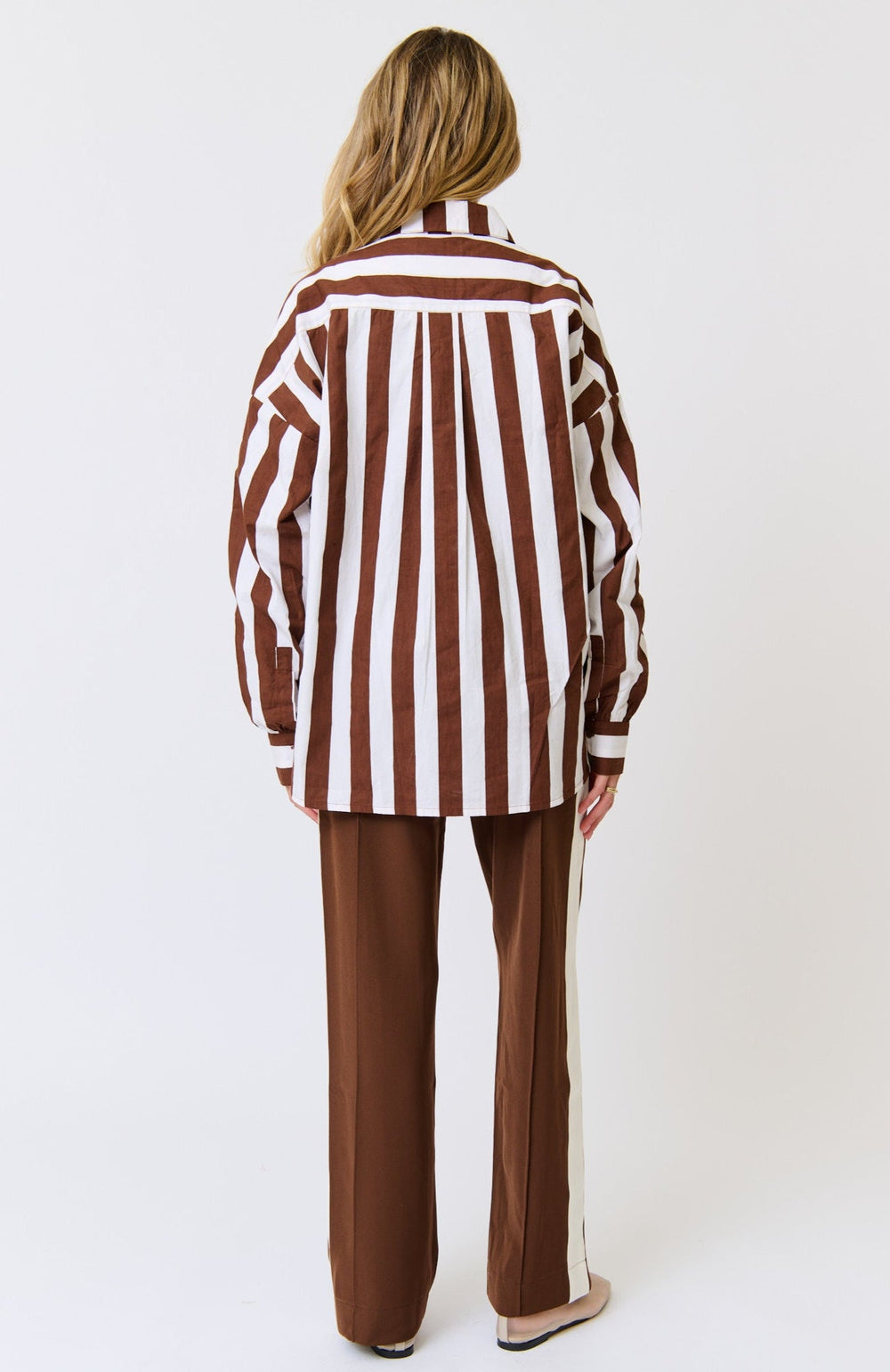 Person wearing a brown and white striped shirt with matching pants on a white background
