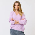 Woman wearing a light purple sweater and blue jeans on a white background