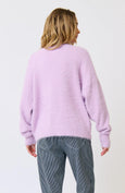 Person wearing a light purple sweater and gray pants on a white background