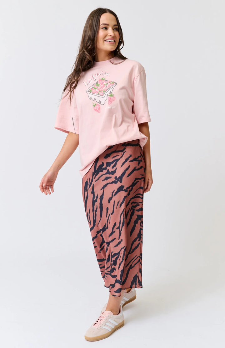 Woman wearing a pink shirt and patterned skirt on a white background