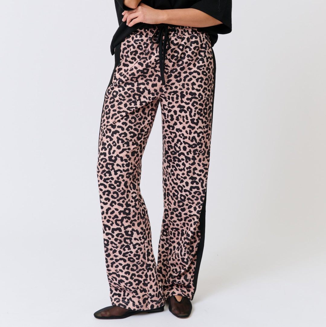 Woman wearing a Cartel & Willow black top and leopard print pants on a white background