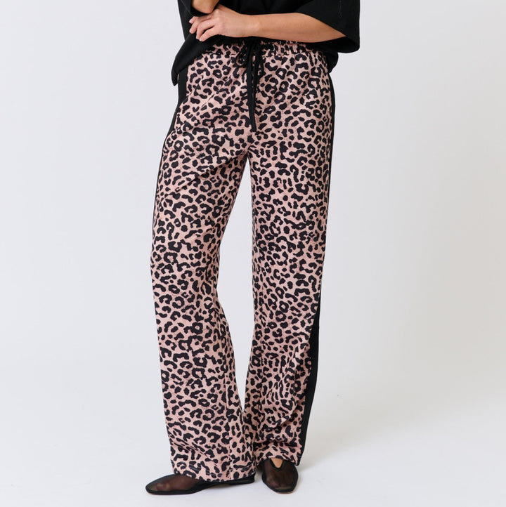 Woman wearing a Cartel & Willow black top and leopard print pants on a white background