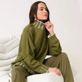 Woman wearing a green outfit sitting on a white chair against a white background