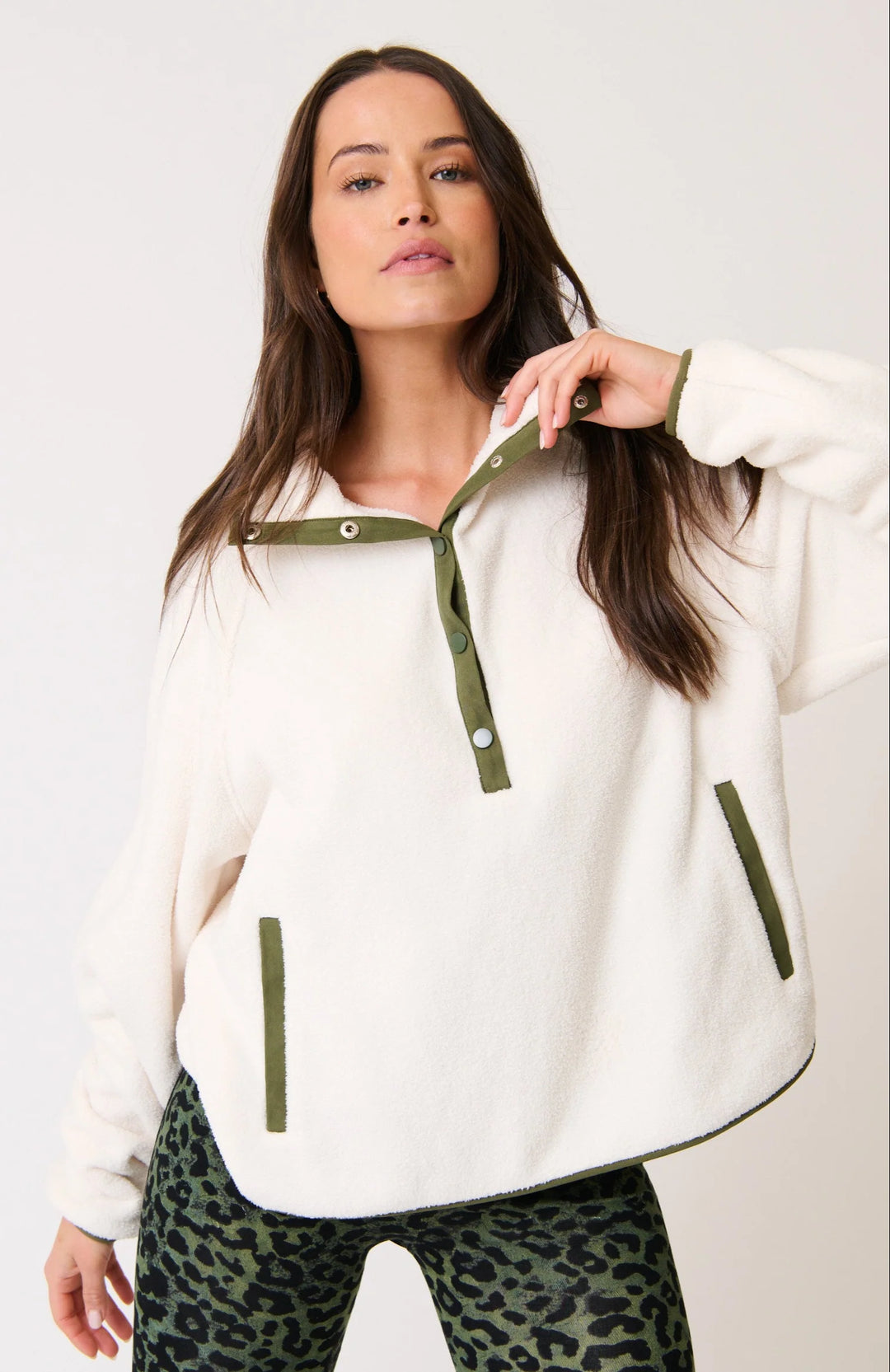 Woman wearing a white hoodie with green accents on a plain background