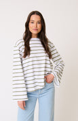 Woman wearing cartel & willow striped long-sleeve shirt and light blue jeans against a plain background