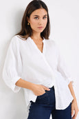 Woman wearing a white blouse and blue jeans against a white background