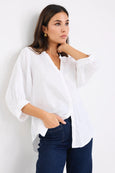 Woman wearing a white blouse and blue jeans against a white background