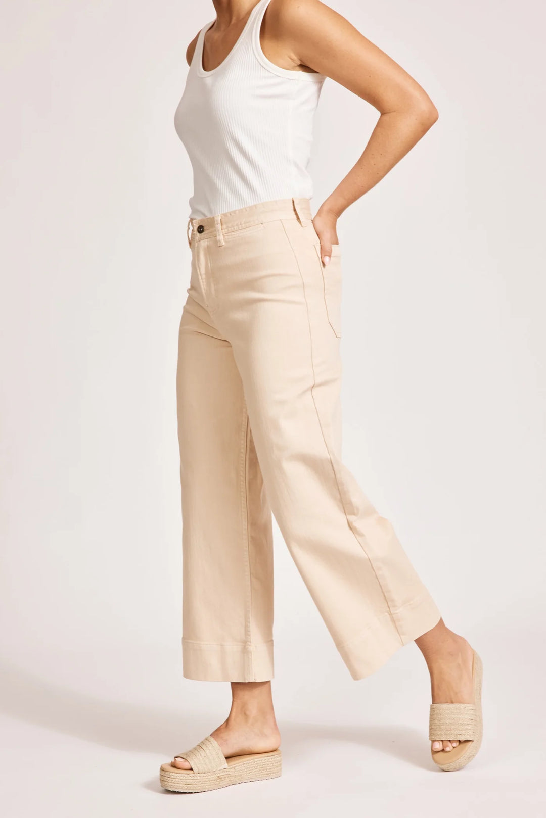 Person wearing Eb & Ive beige pants and a white top on a light pink background