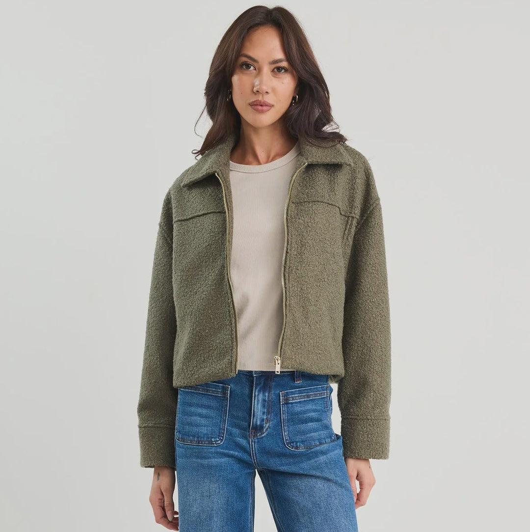 Woman wearing a green jacket and blue jeans on a white background