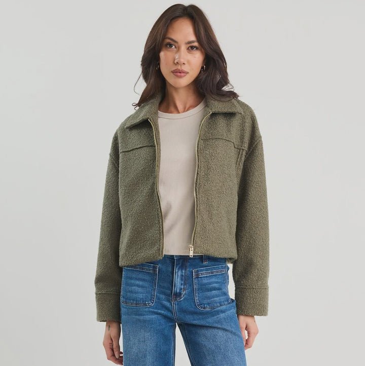 Woman wearing a green jacket and blue jeans on a white background